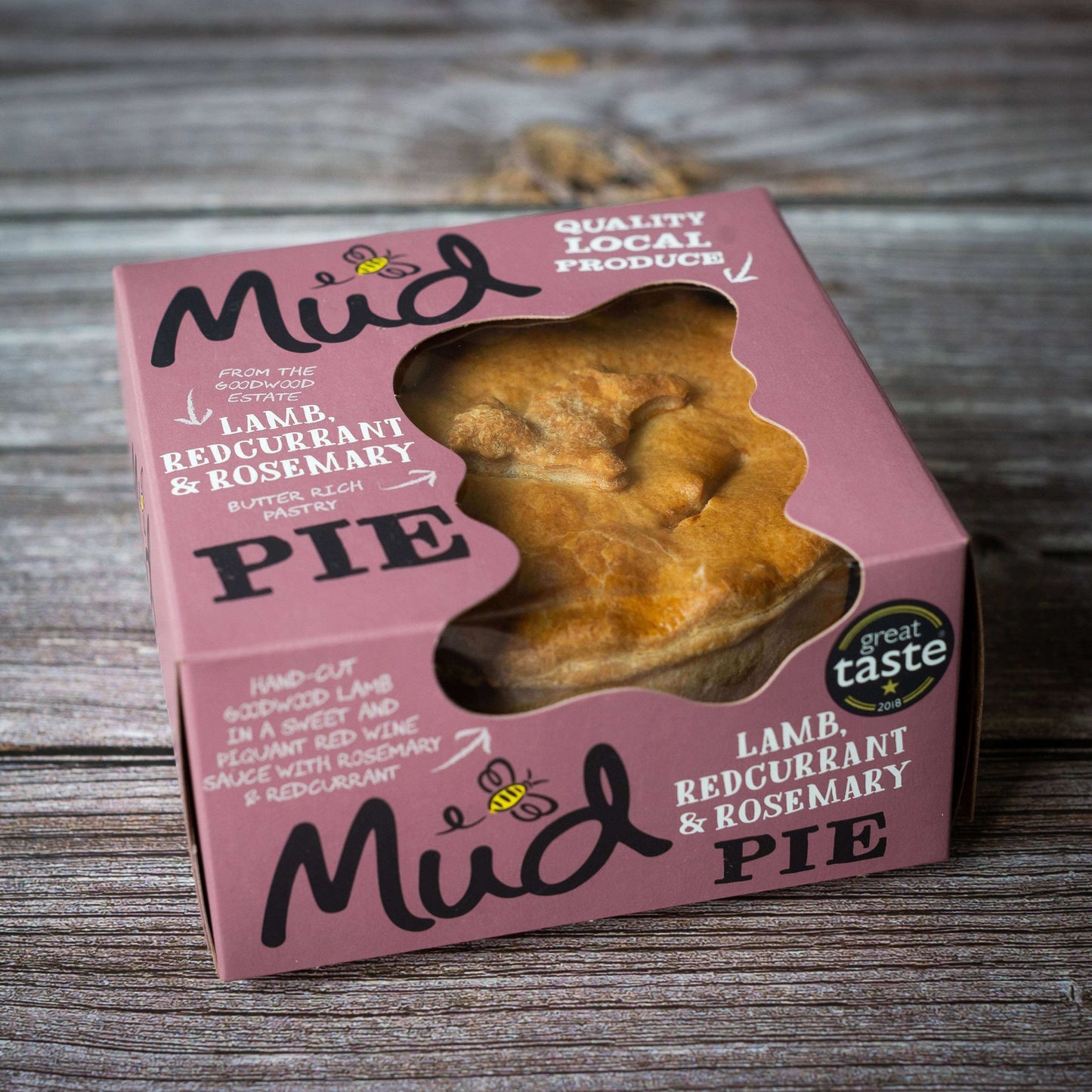 A Mud Pies Lamb, Redcurrant Rosemary Pie in a pink window box sits on wood; label notes redcurrant, rosemary, and awards.