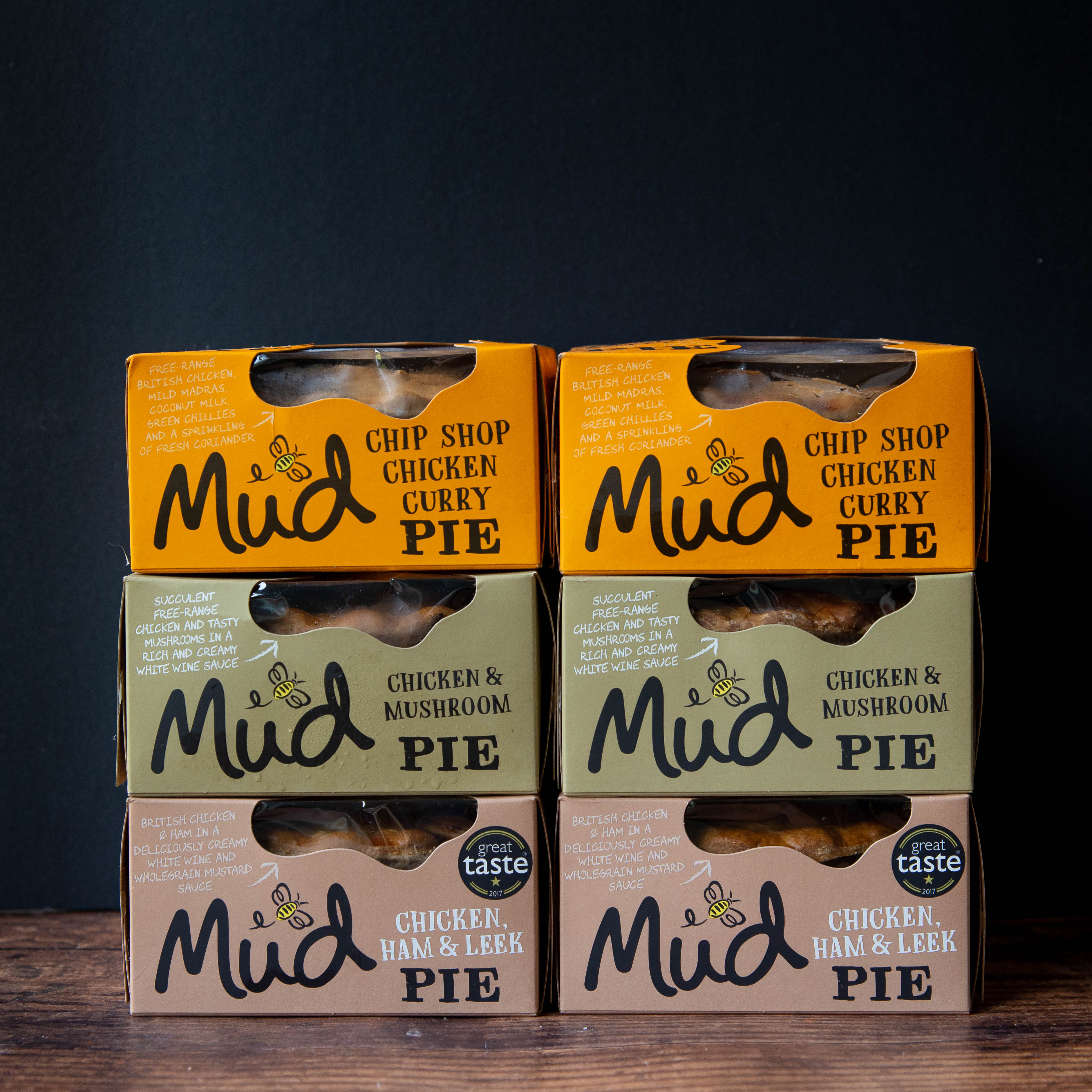 Six Mud Pies Chicken Pie Box 6 Pack, with Chip Shop Chicken Curry, Chicken Mushroom, and Chicken Ham Leek pies stacked in two neat columns on a dark background.