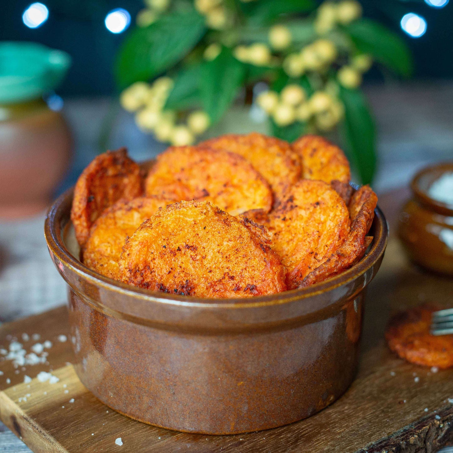 Mud Pies Southern Fried Potatoes, golden and crisp, sit in a brown ceramic bowl on wood, with fairy lights and foliage behind.