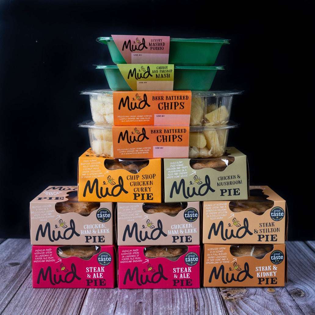 Mud Pies Best Sellers Dinner displayed on wooden table, showcasing steak pie, chicken mushroom, chip shop curry, chips and vibrant sides.