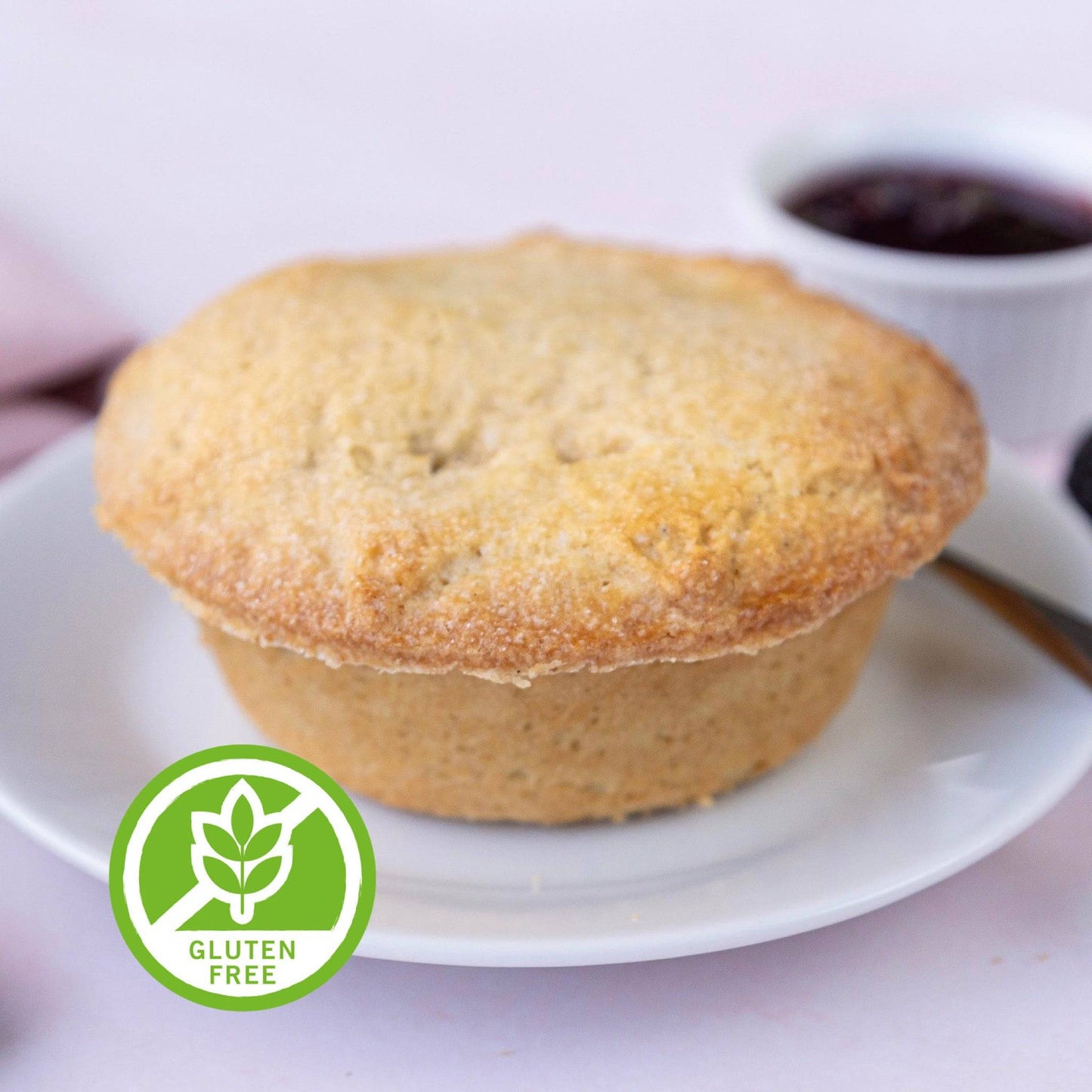 Mud Pies Gluten-Free Apple and Blackberry Pie, golden-brown on a white plate, with jam behind and a green gluten-free badge nearby.