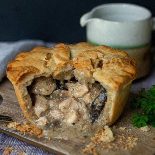 The Mud Pies Chicken and Mushroom Pie boasts golden, flaky pastry with creamy chicken, wild mushrooms and sauce, slice cut to show filling.