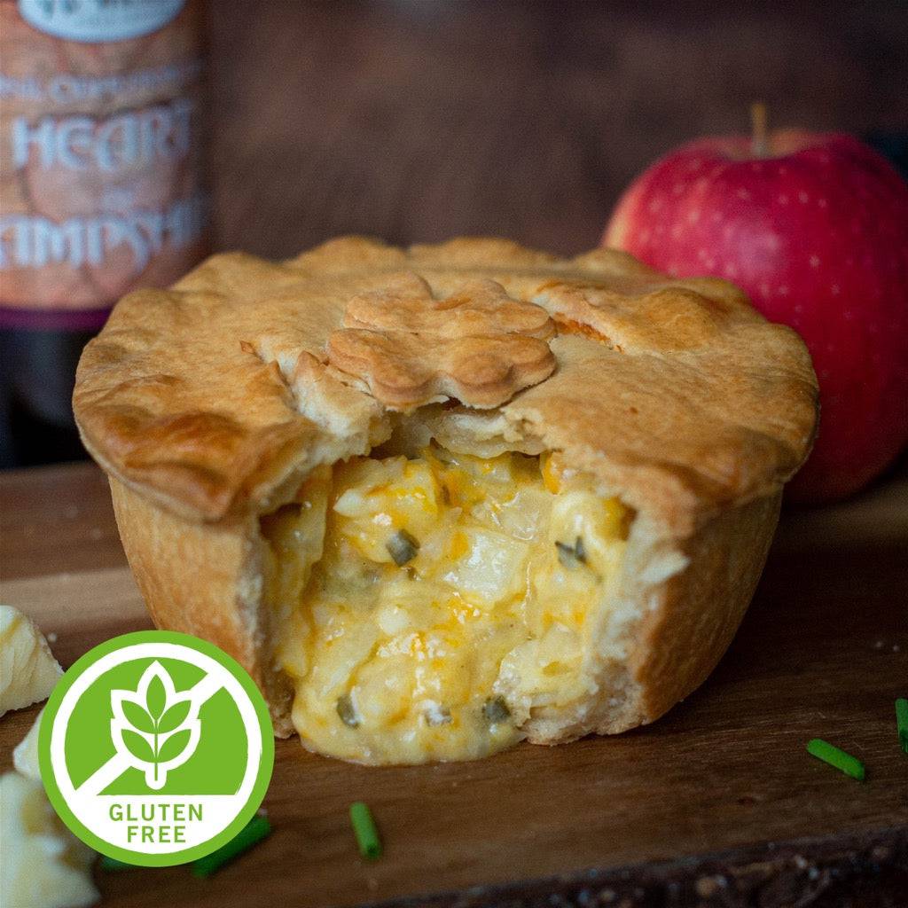 The Mud Pies Gluten-Free Scrumpy Cheese and Onion Pie, with golden flaky pastry and rich filling, sits on wood by an apple and Gluten Free badge.