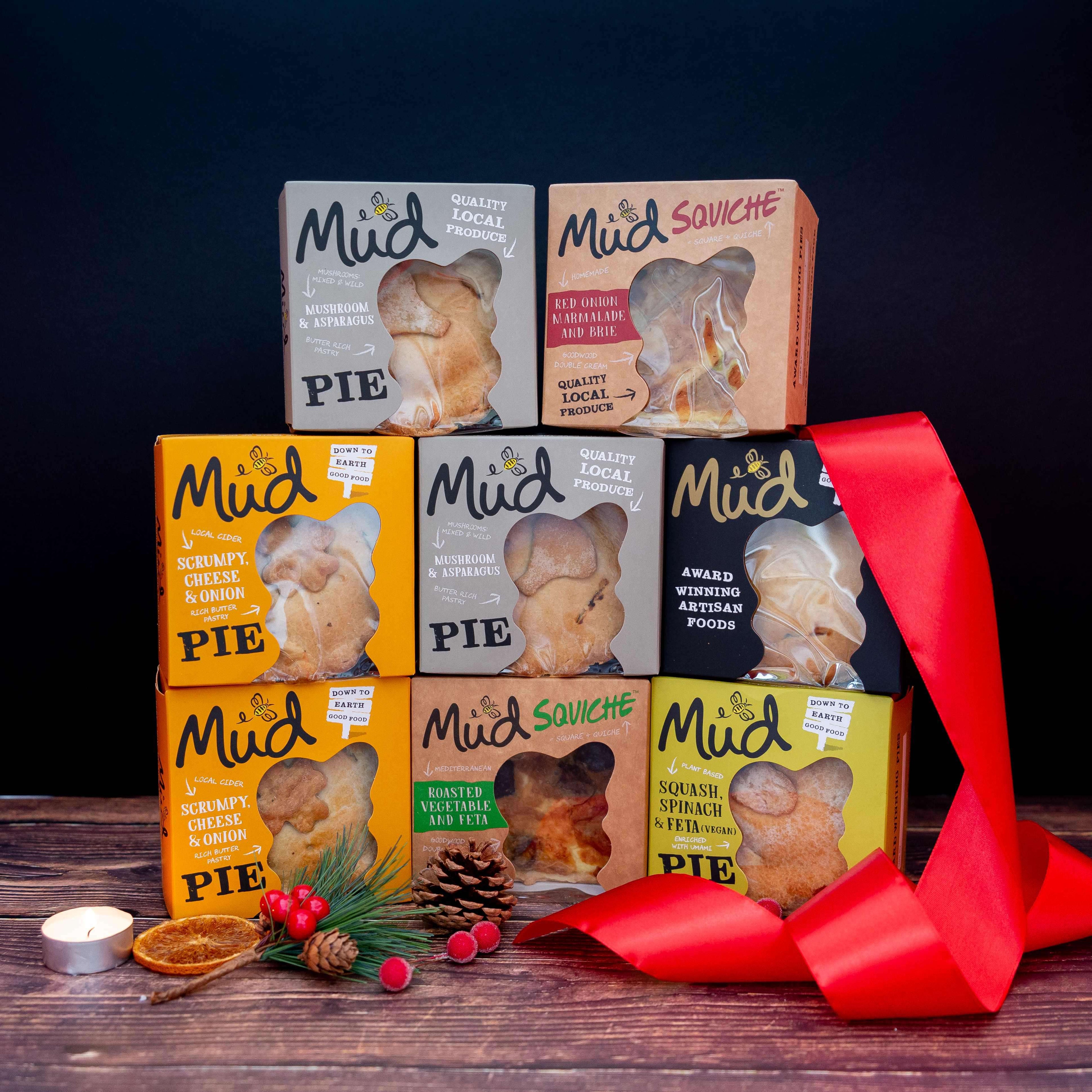 Mud Pies’ Best Ever Vegetarian Christmas Gift Box: seven vibrant veggie pies stacked pyramid-style amid festive décor on wood.