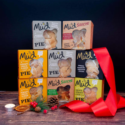 Mud Pies’ Best Ever Vegetarian Christmas Gift Box: seven vibrant veggie pies stacked pyramid-style amid festive décor on wood.