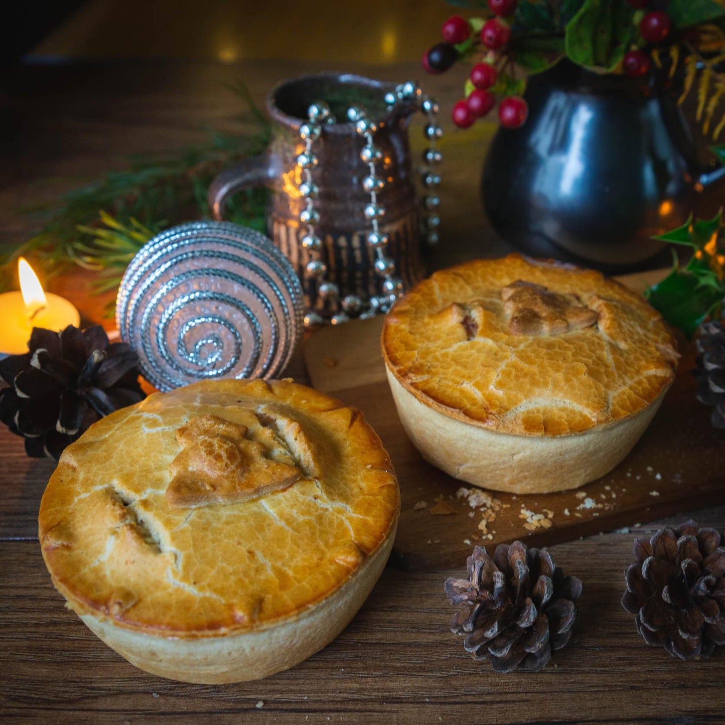 The Luxury Christmas Collection Gift Box by Mud Pies displays golden venison pies among pinecones, candles, ornaments, and festive greenery.
