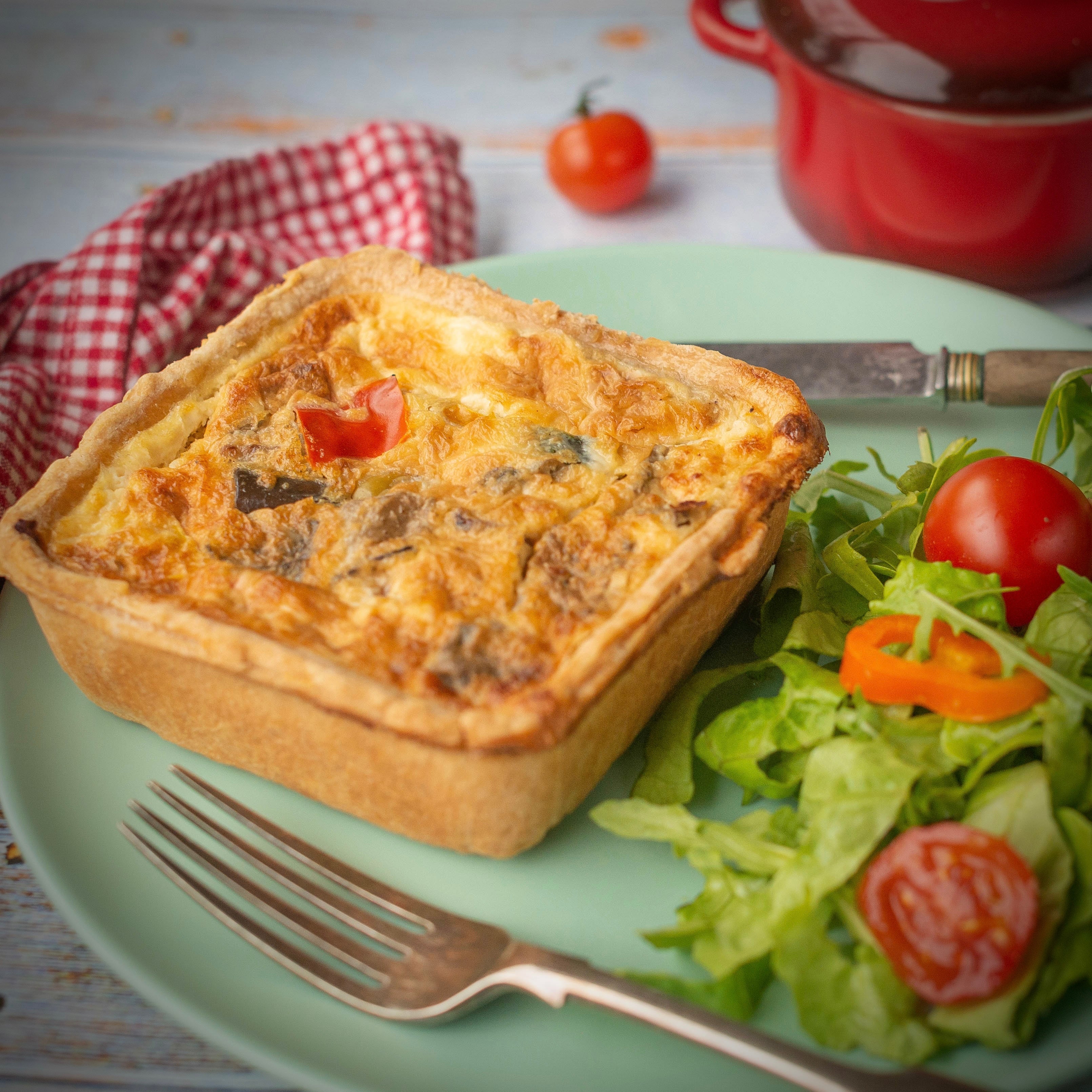 The Best Ever Vegetarian Christmas Gift Box by Mud Pies shows a golden square veggie pie on a green plate with salad and festive tableware.