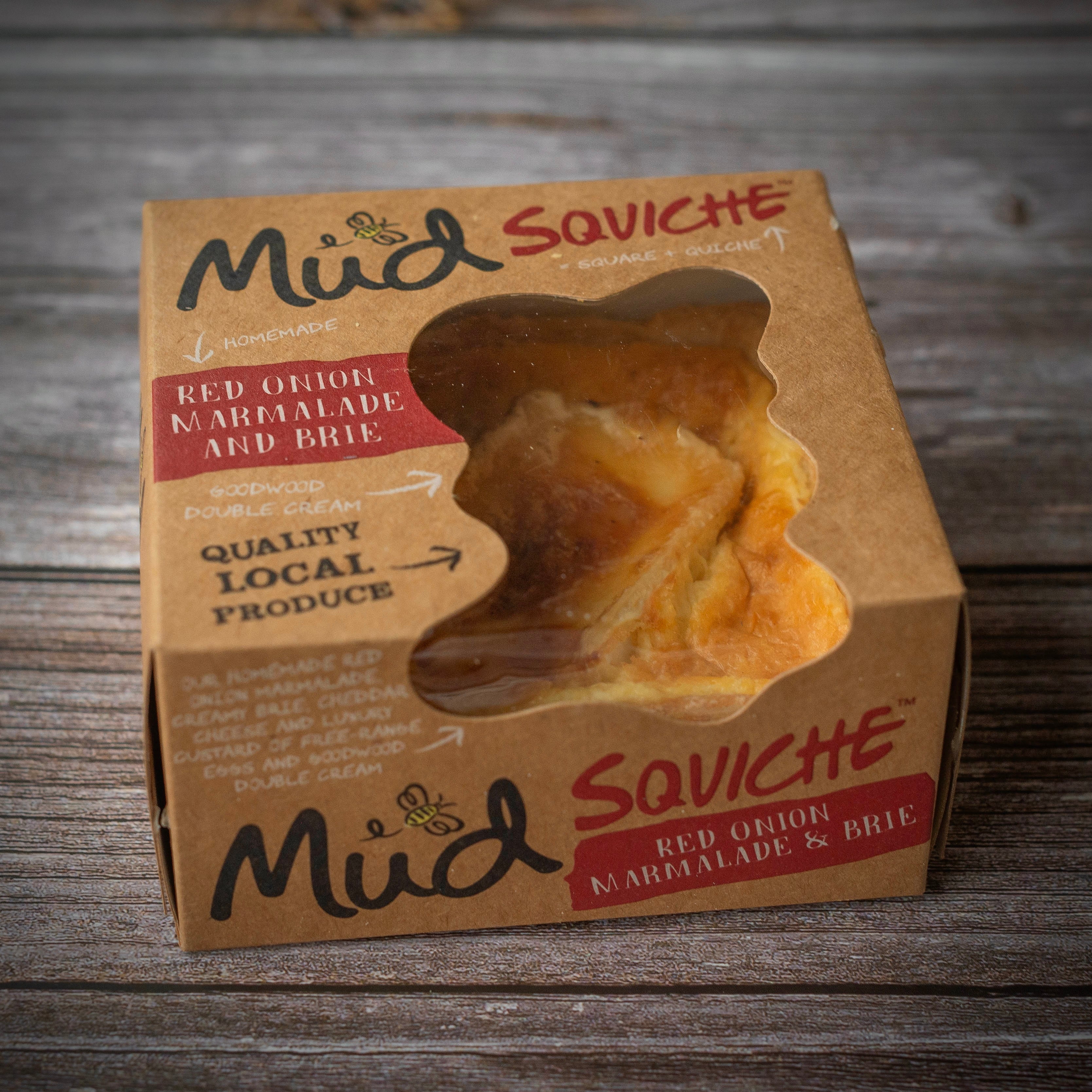 A brown cardboard box with a clear window reveals a baked pastry, labelled “Best Ever Vegetarian Christmas Gift Box” by Mud Pies.