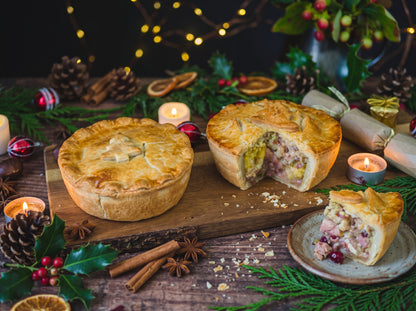 Christmas In A Pie — Turkey and Ham Christmas Pie on a wooden board surrounded by festive decorations.