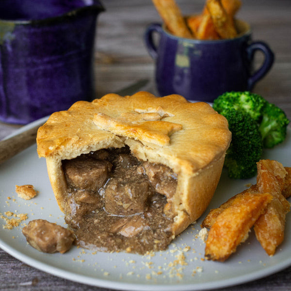 Mud Pies Game Pie has a golden, flaky crust packed with hearty meat and gravy, served with chunky carrot chips and tender broccoli.