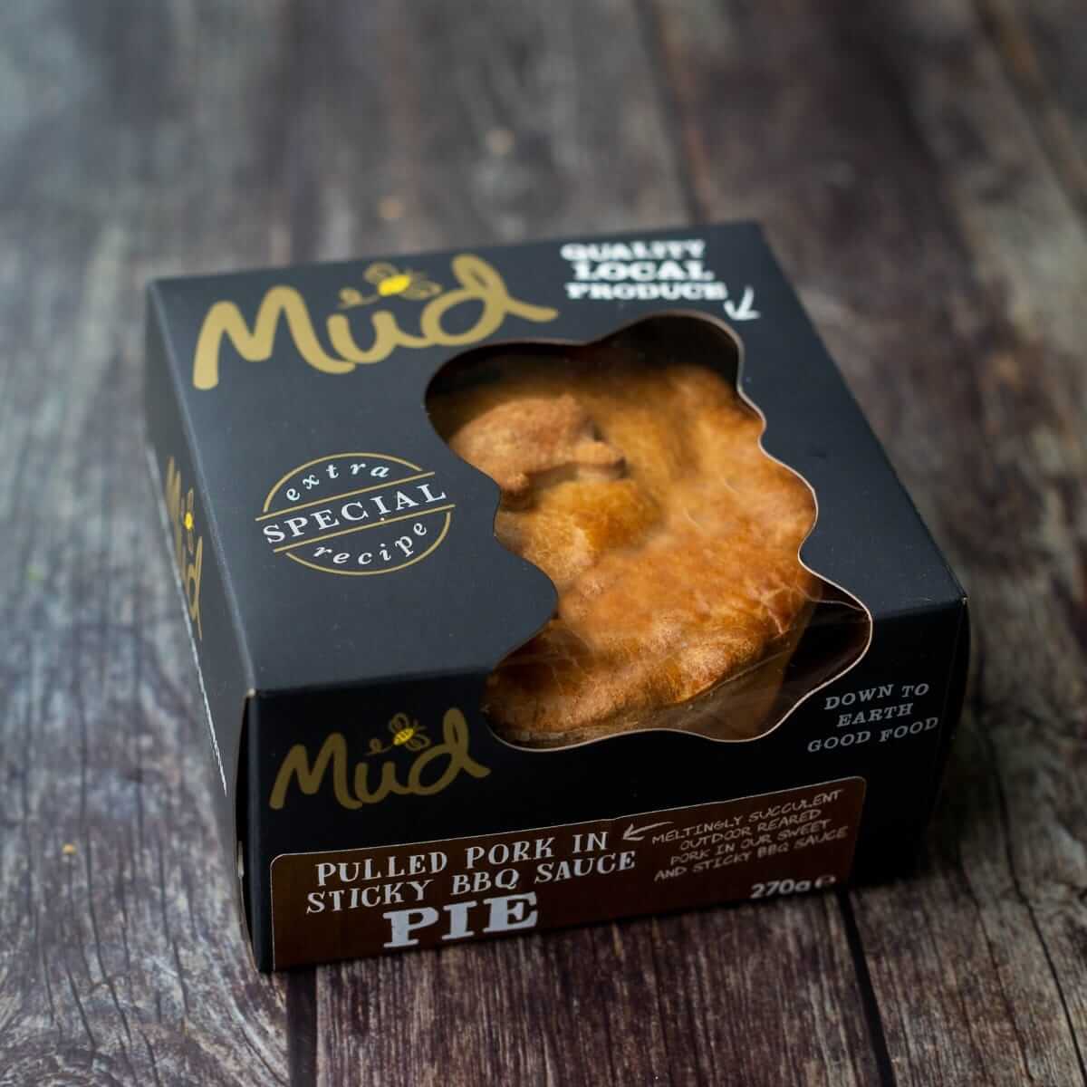 Mud Pies’ “Try Me 5 Bundle” boxed pie sits on rustic wood; elegant black box with gold and white text, crust shows in clear window.