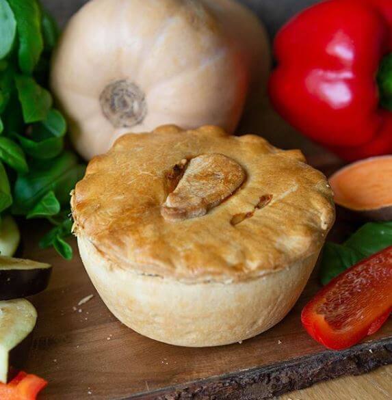 The Best Ever Veggie Gift Box by Mud Pies shows a golden, plant-based pie with ornate pastry, ringed by vibrant fresh vegetables.