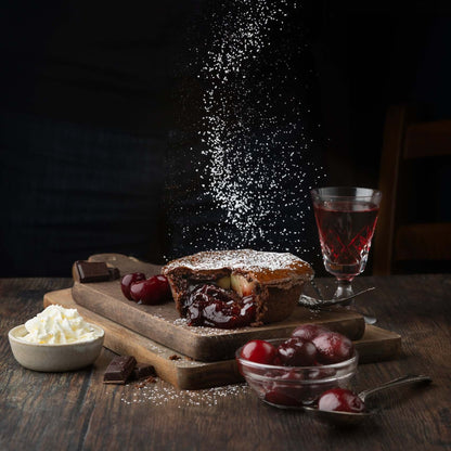 Mud Pies’ limited edition Black Forest Gateau Pie, filled with rich cherry compote and icing sugar, on a board with cherries, chocolate, cherry cordial and whipped cream.