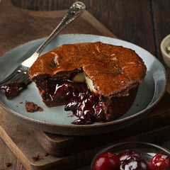 Mud Pies’ limited edition Black Forest Gateau Pie, golden crust and rich cherry filling, on a grey plate with fork and cherries.