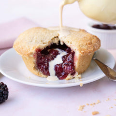 Mud Pies' Apple and Blackberry Pie boasts golden all-butter pastry, a rich fruity filling, and cream, served on white china.