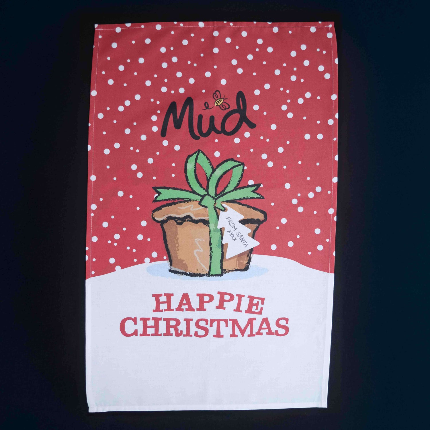 The Mud Pies Tea Towel Christmas is pure cotton, with red snowflakes, snowy white accents, and a festive potted plant. Gift boxed and bearing “HAPPIE CHRISTMAS,” it’s perfect for festive cheer.