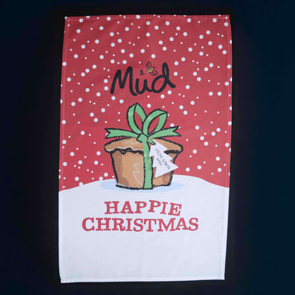 The Mud Pies Tea Towel Christmas is pure cotton, with red snowflakes, snowy white accents, and a festive potted plant. Gift boxed and bearing “HAPPIE CHRISTMAS,” it’s perfect for festive cheer.