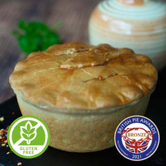 Mud Pies Gluten-Free Chip Shop Chicken Curry Pie, golden-brown, rests on a dark surface with award and gluten-free badges in front.