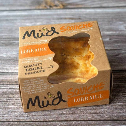 Mud Pies Quiche Lorraine box sits on wooden boards, its window revealing quiche with British bacon, cheddar, and double cream.