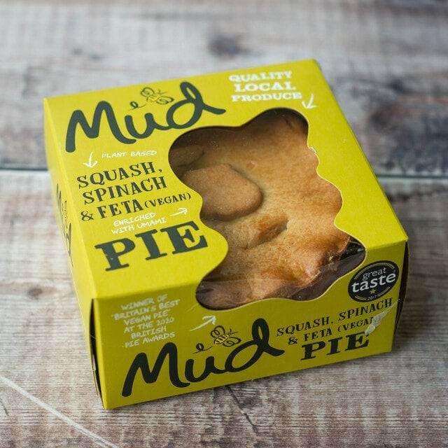 A boxed Mud Pies Squash, Spinach Feta Pie in yellow packaging on wood, golden pastry visible with "quality local produce" and "great taste" labels.