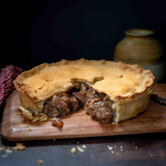 Steak and Ale Family Pie (Serves 4) on a wooden board, showcasing tender beef and a golden crust.