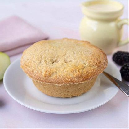 Mud Pies’ Apple and Blackberry Pie, golden-brown pastry on a white plate, with green apple, blackberries, yellow jug of cream and fork.