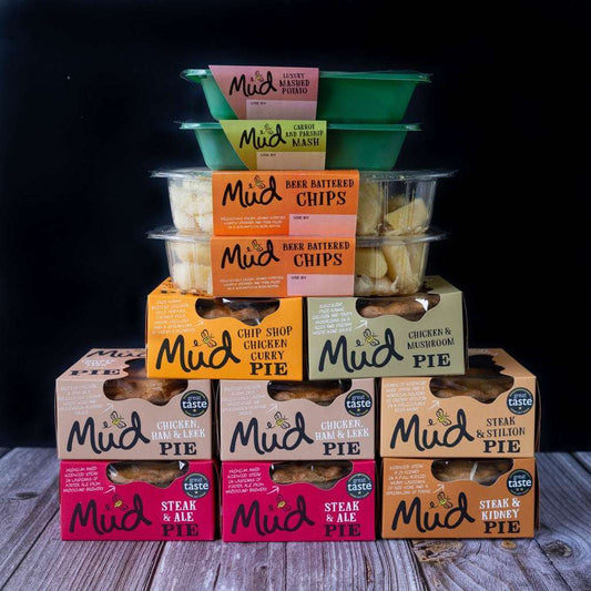 Mud Pies Best Sellers Dinner displayed on wooden table, showcasing steak pie, chicken mushroom, chip shop curry, chips and vibrant sides.