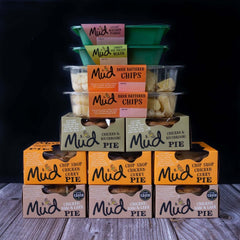 Mud Pies' Chicken Dinner selection: chunky chicken pies, beer battered chips in clear tubs, and mashed potato cups on wood.