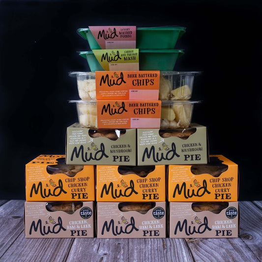 Mud Pies' Chicken Dinner selection: chunky chicken pies, beer battered chips in clear tubs, and mashed potato cups on wood.