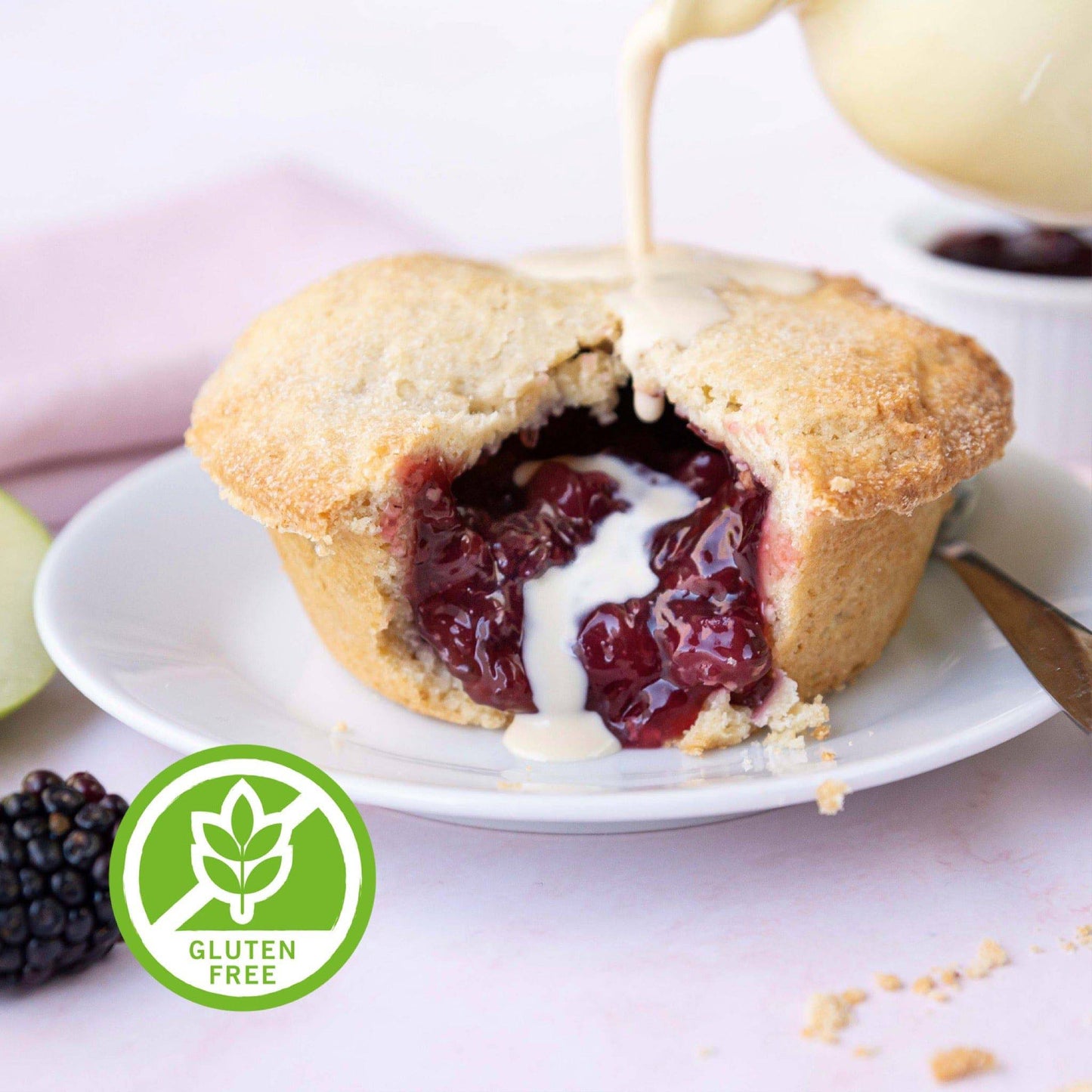 Mud Pies Gluten-Free Apple and Blackberry Pie boasts golden shortcrust pastry, glossy fruit filling, cream, berries, and a green label.