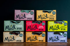 Mud Pies: Eight boxed pies in two neat rows, each vibrant pack showing best-selling flavours, set against a dark backdrop.