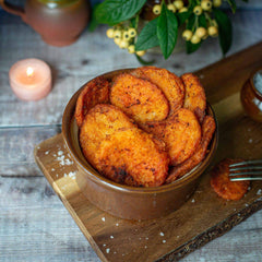 Mud Pies’ Southern Fried Potatoes, golden and crispy, in a brown ceramic bowl on a wooden board with coarse salt and cosy decor.